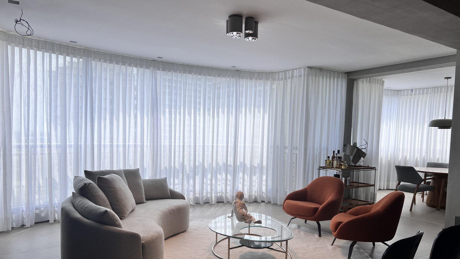 Sala com cortinas de voil sob medida acompanhando a fachada curva